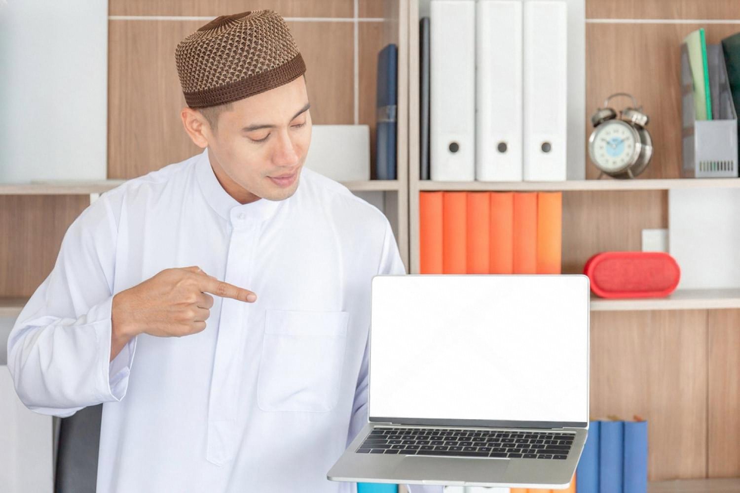 UAE entrepreneur in a white kandura pointing to a laptop screen showing business documents